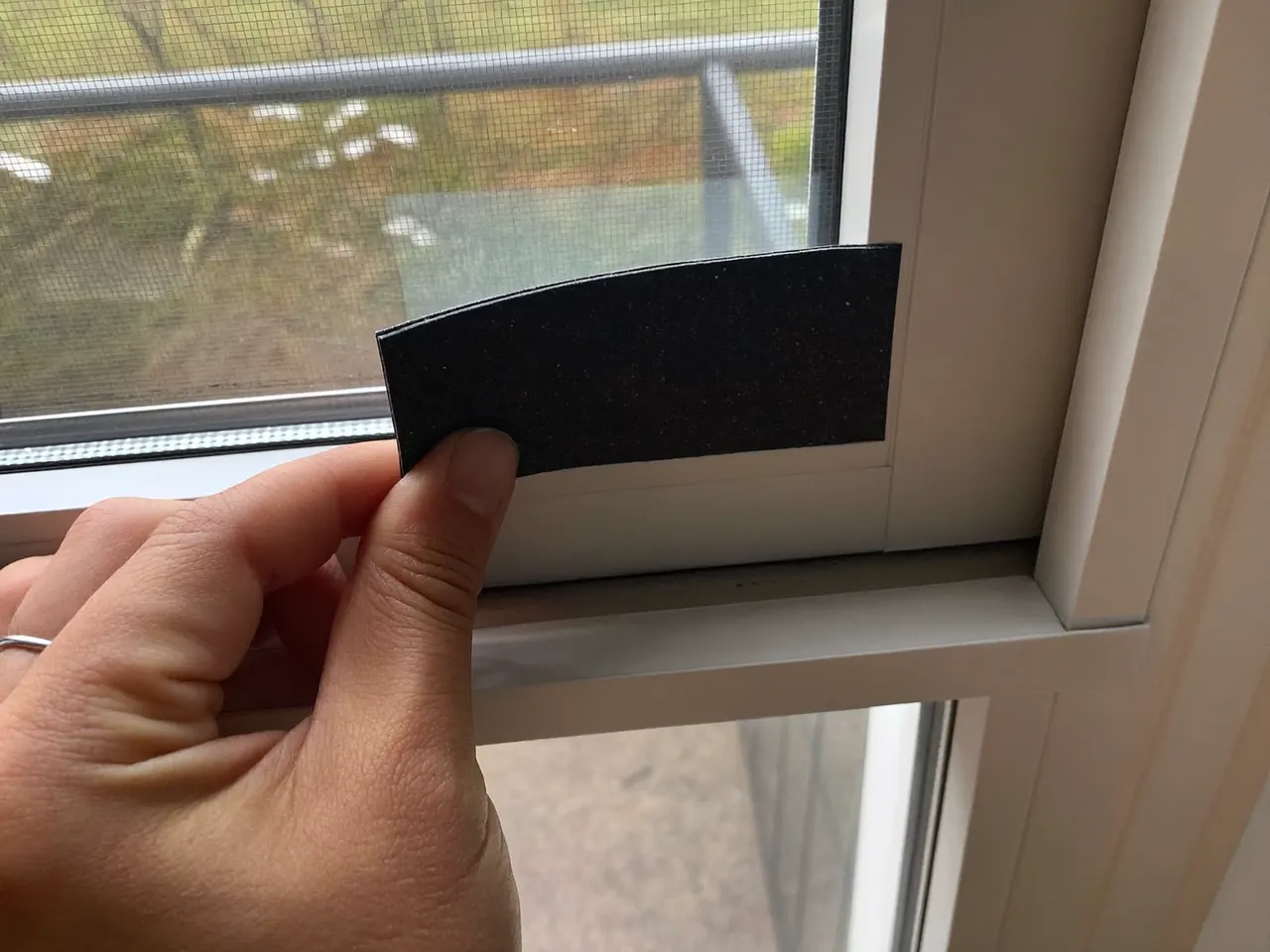 Hand fitting a draught-proofing strip to a window frame